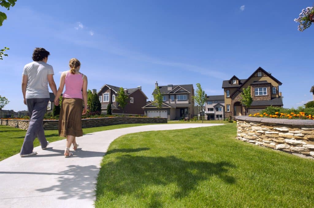 Young couple walking in the suburbs towards a house